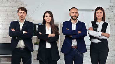 Group of friendly stylish young business people in suit posing with crossed hand at office