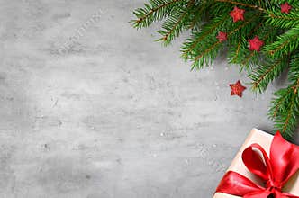 Christmas presents with red ribbon on gray background in a frame made of fir branches with star. Flat lay, top view. Christmas