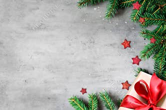 Christmas presents with red ribbon on gray background in a frame made of fir branches with star. Flat lay, top view. Christmas