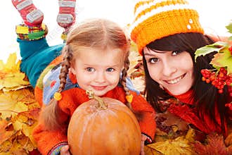 Happy family with pumpkin on autumn leaves.