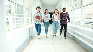 Slow motion of students running in college hall doing high-five jumping laughing