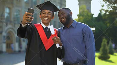 Happy university student graduation mantle and father taking selfie smartphone