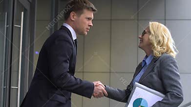 Young male applicant greeting HR employee, hurrying to office for job interview
