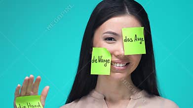 Happy female with sticky notes, learning body parts in German, education