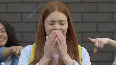 Cruel teens pointing at ginger girl, teasing about red hair, school bullying