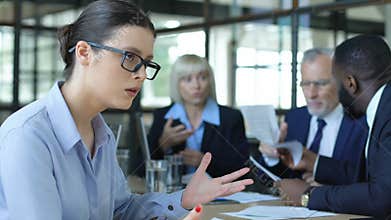 Woman employee shocked with quarreling business people at meeting, office mess