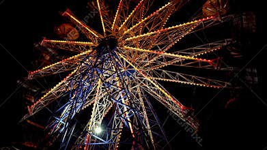 Carnival Ferris Wheel with lights at night. Families with kids celebrate summer.