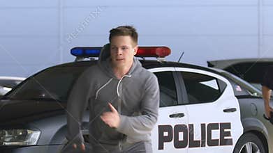 Policeman aiming gun at running criminal in hoodie, detention of thief, slow-mo