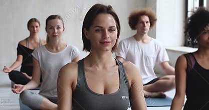 Caucasian female yoga coach and multiracial people meditating indoors