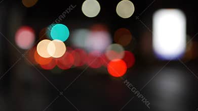 Beautiful glittering bokeh in dark blurry background at night. The round colorful bokeh shine from car lights in traffic