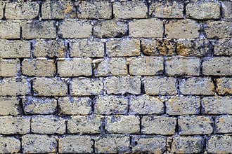 Old shabby beige castle wall made of concrete gray bricks. rough surface texture