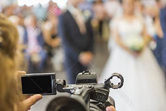 Screen and part of a video camera of an operator taking an event or a wedding.