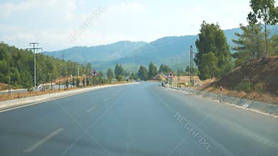 Point of view of car driving at road in scenic mountain environment. Auto riding through highway at summer day