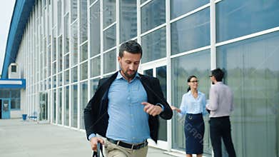Slow motion of handsome young man running with briefcase along office building