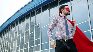 Portrait of funny man making superhero gestures then running to big business