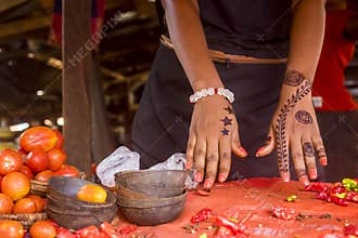 African lady showcasing the henna tattoo drawing on her hand in a local market.