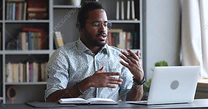 Serious african businessman wear headset conference calling by webcam