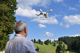 Senior man navigates unmanned aerial vehicle among nature