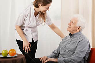 Old man in nursing home with helpful carer
