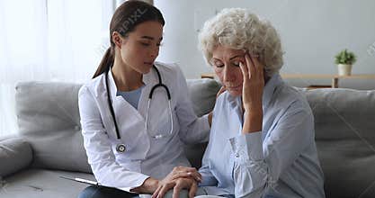 Young woman nurse doctor supporting comforting depressed old grandma patient