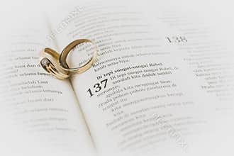 old wedding ring between holy Bible page, symbol of loyalty and long marriage. matte tone