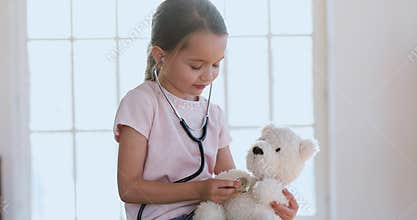 Cute little girl playing as doctor treat teddy bear