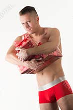 Young man in red mens underpants standing and holding present boxes