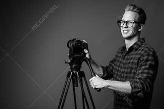 Young handsome hipster man vlogging with camera in black and white
