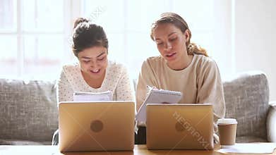 Two happy diverse girls students friends studying together at home