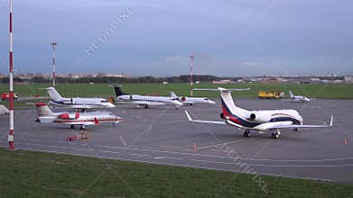 At the airport parking lot, aircraft are parked. Plane lands on the runway. 4K
