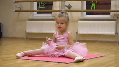 Little ballerina in pink dress doing choreography practice