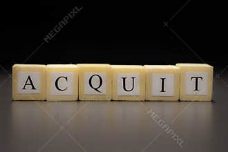 The word ACQUIT written on wooden cubes isolated on a black background
