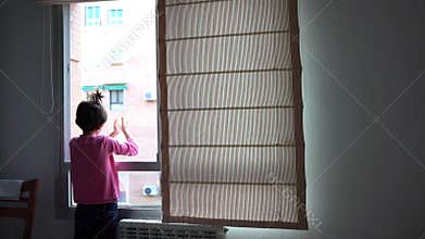 Girl clapping in the window in support of people who fight against the coronavirus
