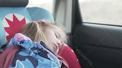 A beautiful little girl sleeps in a car in a car seat