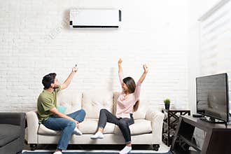 Couple Sitting Below Mini Split On Sofa At Home