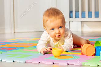 Baby toddler boy play and crawl in front of crib