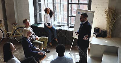 Confident coach joking with company staff at workshop in office.