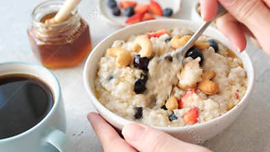 Eating oatmeal porridge with fresh berries for breakfast