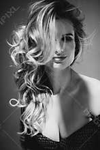 Close-up portrait of a beautiful romantic girl with sexy full lips and developing curls in the sun. Black and white photo art.