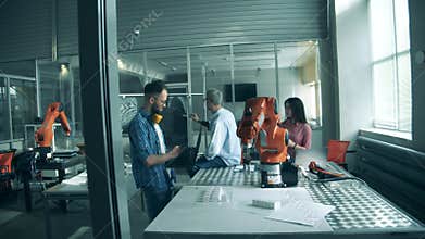 Young engineers are supervising an experiment with lab robots