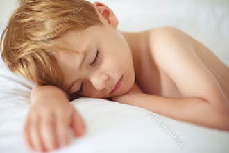 Cheerful boy sleep in bed.