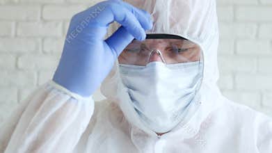 Doctor arranging his protection suit wearing gloves, mask, and eyeglasses in hospital quarantine