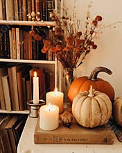 pumpkins and candles on a shelf with books