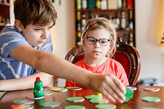 Family playing board game at home. Kids play strategic game. Little sister girl and school brother boy. Fun indoor