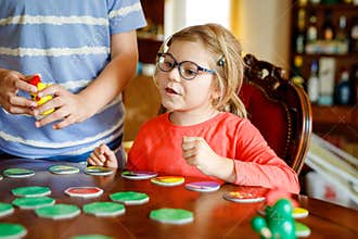Family playing board game at home. Kids play strategic game. Little sister girl and school brother boy. Fun indoor
