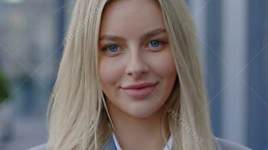 Confident young blonde businesswoman stands outside the office building and looking at camera. Female Maneger Posing