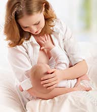 Mother feeding breast her baby in bed