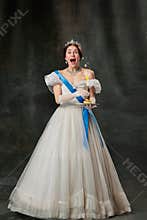 Happy birthday. Elegant woman, royal person, queen or princess in white medieval outfit tasting cake on dark vintage