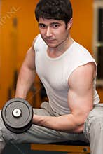 Young man lifting dumbell at fitness gym