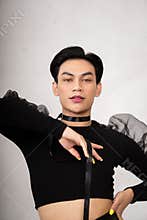 A transgender man poses in a black dress with an elegance face and black hair